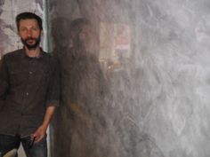 a man standing next to a wall in a room with peeling paint on the walls