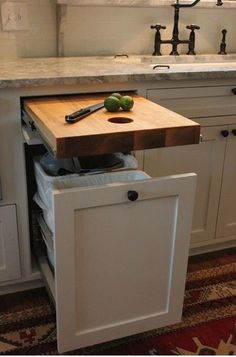 a kitchen with a cutting board and knife on the counter top next to an open drawer