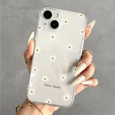 a woman holding up her phone case with daisies on it