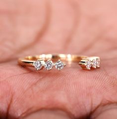 a person's hand holding a gold ring with three small diamonds on top of it