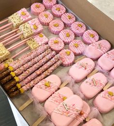 a box filled with lots of pink and yellow decorated cookies next to marshmallows