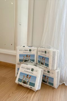 three packs of eco - natty diapers sitting on the floor in front of a mirror