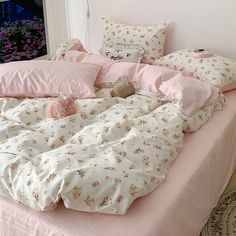 a bed with pink sheets and pillows on it