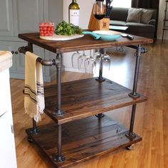 a kitchen island with wine glasses on it and some vegetables in the middle, sitting on top of a hard wood floor