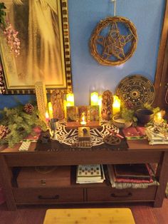 a wooden table topped with lots of candles next to a painting and other items on top of it