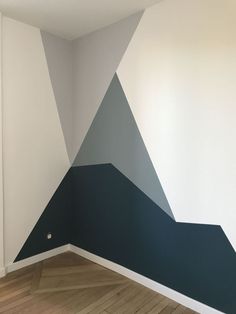 an empty room with a painted triangle on the wall and wood flooring in front of it