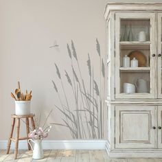 a white cabinet sitting next to a wall with a shadow of grass on the wall