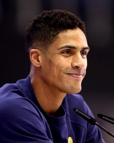 a close up of a person sitting at a table with a microphone in front of him