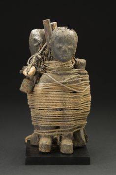 an old wooden statue with rope wrapped around it