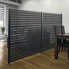 a dining room table with chairs and a sliding gate in front of the wall that is made out of metal slats