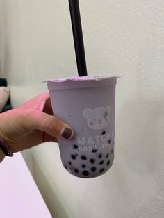 a person holding up a cup with a black straw in it's mouth and the words hello kitty on it