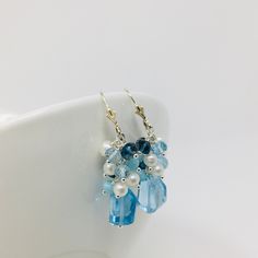 One of a kind Blue Topaz Cluster Earrings, are a perfect way to add a burst of color to any outfit. The fabulous array of colored gems include Sky Blue Topaz, Larimar, London Blue Topaz and Small Freshwater Pearls. This beautiful bouquet of gems sits on top of a unique asymmetrical large Sky Blue Topaz gemstone. Sterling Silver findings, lever back Earwires with a 2 inch drop length. Each set is personally handcrafted , so no two sets are identical. Handmade and designed in Stuart, FL and shipped from the US * In order to create unique and distinctive pieces, I use diverse shapes of natural gems to ensure that no two pieces are exactly the same. As such, each gem in hand-picked and inspected to ensure quality. However, I cannot create exact replications of any piece due to the natural vari Blue Topaz Earrings With Gemstone Accents, Light Blue Gemstone Earrings - Fine Jewelry, Blue Topaz Briolette Gemstone Earrings, Blue Faceted Drop Earrings, Fine Jewelry Blue Aquamarine Earrings, Blue Aquamarine Earrings Fine Jewelry, Blue Aquamarine Fine Jewelry Earrings, Blue Cluster Drop Earrings As Gift, Blue Drop Cluster Earrings For Gift