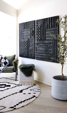 a living room with two black and white panels on the wall, a green plant in a pot and a small stool