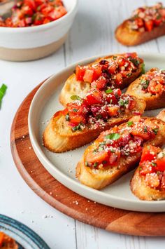 several pieces of bread on a plate with tomatoes and seasoning sprinkles