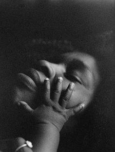 a black and white photo of a person covering their face with his hands while holding the other hand