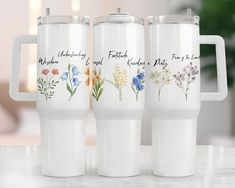 three white travel mugs with floral designs on them