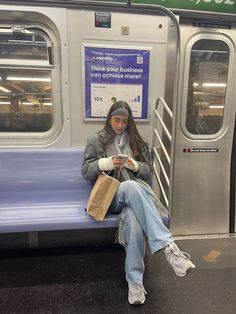 a woman sitting on a subway bench looking at her cell phone