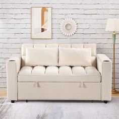 a white couch sitting in front of a brick wall with a lamp on top of it