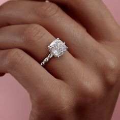 a woman's hand holding an engagement ring with a diamond in the shant