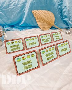 four place cards are sitting on a table next to a fan and vase with flowers