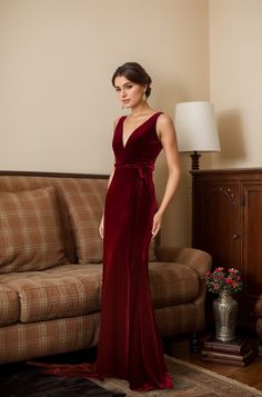 a woman standing in front of a couch wearing a red dress