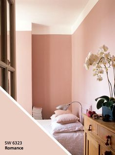 a bedroom with pink walls and white flowers in vases on the dresser next to it