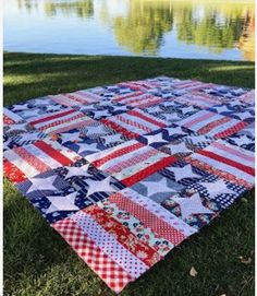 an american flag quilt on the grass by water with trees in the backgroud