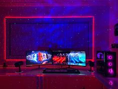 two computer monitors sitting on top of a desk in front of a purple and blue light