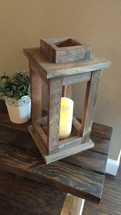 a wooden lantern sitting on top of a table next to a potted plant