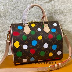 Spring/Summer New Products Presbyopia Polka Dot Print Speedy Bandoulière 25 handbags are made of metal texture coated canvas, presenting the eye-catching blooming of gorgeous buttercups, telling about the flowers that Nicolas Ghesquière cultivated for the 2022 Autumn/Winter fashion show theme. The classic silhouette enhances the romantic mood, and the rolled leather handle and detachable shoulder strap allow multiple carrying options. 

Dimensions 25 x 19 x 15. Luxury Multicolor Bag With Adjustable Strap, Luxury Multicolor Satchel With Adjustable Strap, Multicolor Coated Canvas Shoulder Bag With Dust Bag, Multicolor Coated Canvas Top Handle Shoulder Bag, Multicolor Top Handle Coated Canvas Shoulder Bag, Winter Fashion Show, Speedy Bandoulière 25, Fashion Show Themes, Louis Vuitton Yayoi Kusama