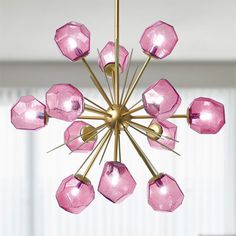 a pink chandelier hanging from a ceiling in a room with white walls and windows