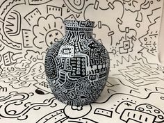 a black and white vase sitting on top of a table next to a drawing wall