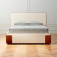 an upholstered bed with two pillows on it