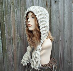 a mannequin head wearing a crochet hat with tassels on it