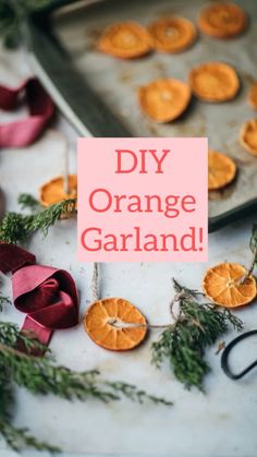 an orange garland on a baking sheet with ribbon around it and some dried oranges in the background