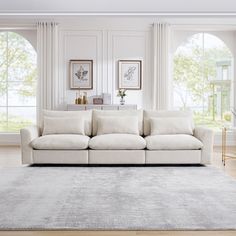 a living room with white furniture and large windows in the back ground, there is a gray rug on the floor