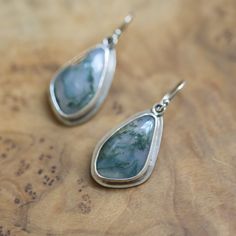 Natural, Moss Agate Drop Earrings. All metal is .925 Sterling Silver. Choose your pair below - your choice will be highlighted in the photo as you choose. These gorgeous, simple, Moss Agate drop earrings feature stunning and natural, Moss Agate irregularly shaped cabochons set in a simple .925 Sterling Silver bezel setting. Just Right! These deep earthy green Moss agate drop earrings switch from data to night while still having the richness and benefits of natural stones. We have pierced the bac Silver Agate Jewelry, Pierced Silver Agate Jewelry, Agate Gemstone Dangle Earrings, Agate Gemstone Earrings Gift, Agate Gemstone Earrings For Gifts, Silver Agate Drop Earrings, Silver Agate Earrings With Natural Stones, Silver Agate Jewelry With Matching Earrings, Unique Silver Agate Earrings