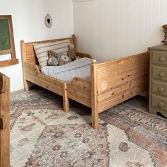 a wooden bed sitting on top of a rug in a bedroom next to a dresser