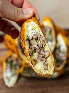 a person is holding a piece of bread with meat and cheese on it as they are about to eat