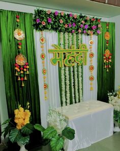 a decorated stage with flowers and garlands on the wall in front of green drapes