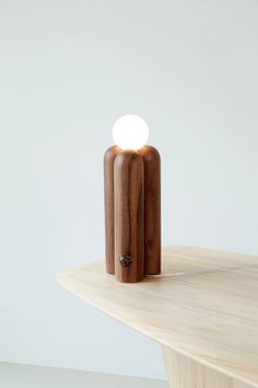 a wooden table with a small light on it's end and a white wall in the background