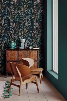 a chair and table in front of a wallpapered room with green plants on it