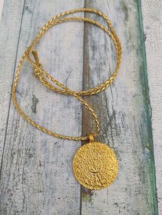 Stunning large Gold Phaistos disk pendant with plaited gold cord (and length of black 2mm cotton cord) This pendant can become a fascinating focal point of conversation and will look stunning in Summer or Winter.  The original Phaistos Disc is on display at the archaeological museum of Heraklion. It is a disk of fired clay from the Minoan palace of Phaistos on the island of Crete, dating to the middle or late Minoan Bronze Age (which is the second millennium BC). The disk is about 15 cm diameter Antique Gold Brass Medallion Necklace, Antique Gold Round Pendant Medallion Necklace, Gold Coin Pendant Necklace For Festival, Spiritual Brass Coin Medallion Necklace, Hammered Brass Coin Pendant Necklace, Bohemian Gold Coin Necklace With Round Pendant, Gold Bohemian Coin Necklace With Round Pendant, Hammered Round Medallion Necklace As Gift, Gold Necklace With Coin Pendant For Festival