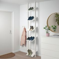 there is a white shelf with several pairs of shoes on it and a plant in the corner