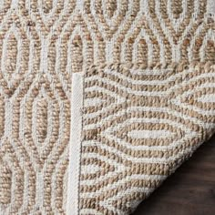 a close up view of a rug on a wooden floor with a brown and white pattern