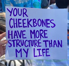 a person holding up a sign that says your checkbones have more structure than my life