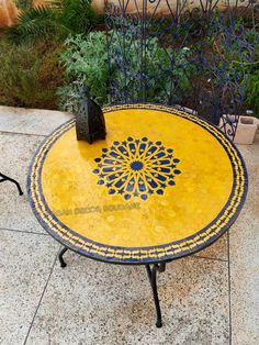 a yellow table sitting on top of a tiled floor next to a potted plant