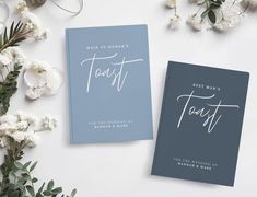 two wedding cards on top of each other next to some white flowers and greenery