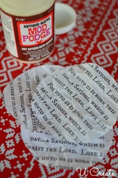 a jar of glue sitting on top of a red table cloth next to some paper