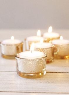 several lit candles sitting on top of a wooden table